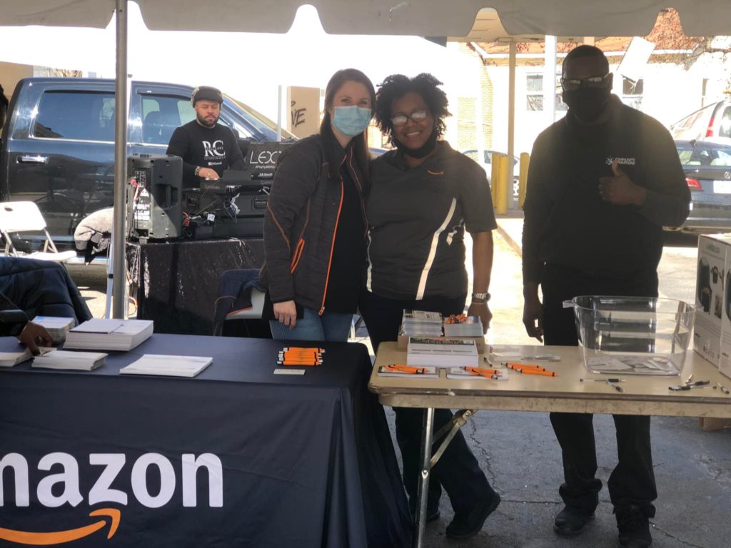 Volunteers standing behind a booth with an Amazon cover.