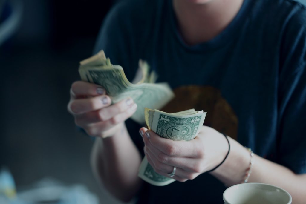 A woman counting a stack of dollar bills by hand.
